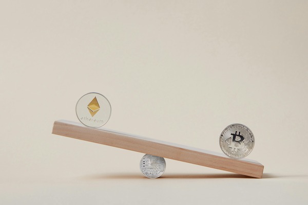 Ethereum and Bitcoin coins balanced on opposite ends of a small wooden seesaw