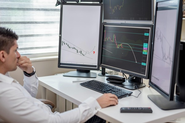 Trader analyzing cryptocurrency price charts across several desktop monitors